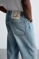 Pantalón de jean celeste de corte amplio, con efecto lavado y roturas.
