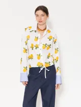 Camisa blanca de poplin con bordado de limones, jareta en la cintura con lazo ajustable, broches dorados, vivos blancos y puños en poplin rayado con ajuste mediante ojal y botón forrado.