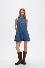Vestido corto de denim azul, sin mangas, con cuello redondo y falda con volados.