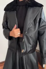 Campera bomber negra de cuero con cuello de piel sintética negra, forro interior y detalles de pasamanería en cuero marrón gastado en las mangas.