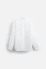 Camisa color beige claro, de corte relaxed fit, confeccionada en tejido de lino y algodón. Tiene cuello mao, manga larga con puños abotonados y cierre frontal con botones.