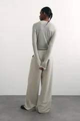 Pantalón de vestir color beige, de corte ancho y tiro alto, con pinzas delanteras, bolsillos laterales y cierre frontal.