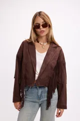 Chaqueta de efecto gamuza en color tostado, con solapas amplias, cierre frontal con un botón y flecos largos decorativos en la parte frontal y trasera de las mangas. Presenta una estructura definida y forro interior.