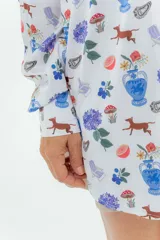 Camisa blanca con estampado de flores, perros, sillas y jarrones.