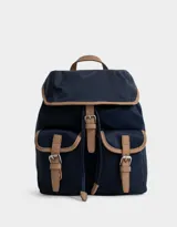 Mochila azul marino con detalles en cuero sintético color camel. Tiene solapa superior con cierre de hebilla, doble bolsillo frontal con hebilla, correa de ajuste y manija superior.