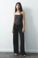 Top bustier negro de satén con escote corazón y hombros descubiertos. Cierre trasero con cremallera metálica.
