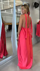 Vestido largo de fiesta color fucsia, con escote halter, espalda descubierta y tajo en la pierna.