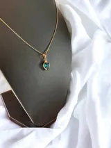 Cadena dorada con colgante en forma de corazón de tonos verdes y azul.