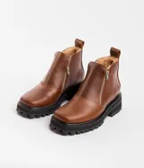 Bota de cuero vacuno color marrón, con interior forrado en corderito natural. Tiene suela de goma artesanal, punta cuadrada, cierre YKK en ambos lados y caña de 11cm.