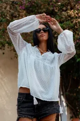 Camisa blanca de plumetí con cuello mao, mangas largas abullonadas con puños elásticos y cordón con borlas en el escote.