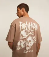 Remera marrón de algodón con efecto desteñido, corte relajado, cuello redondo, mangas cortas y estampa de calaveras con texto "Forsaken Born Freak".