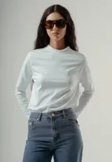 Camiseta de manga larga color blanco, con cuello mock (cuello mao o cuello tortuga bajo) deshilachado. Presenta un pequeño bordado sutil en el pecho.