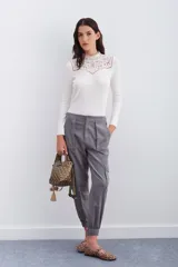 Pantalón de corderoy gris, de corte holgado, con elástico en la cintura, cierre y botón. Tiene bolsillos aplicados en el delantero y puños de piernas con elástico interno.