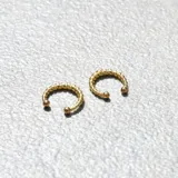 Par de aros tipo cuff dorados con diseño trenzado y bolitas en los extremos.