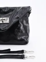Cartera tipo sobre de cuero sintético color negro con cierre metálico plateado.