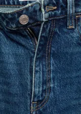 Pantalón de jean azul de corte mom, con tiro alto, cinco bolsillos y cierre de cremallera y botón.
