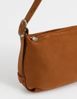 Bandolera color marrón camel de cuerina con textura gamuzada, asa corta de hombro y charm lateral.