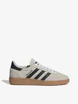 Championes Adidas Handball Spezial color crema con las tres tiras laterales en negro y suela de goma marrón.