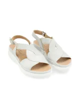 Sandalias de cuero color gris claro con tiras cruzadas y elástico. Suela de plataforma blanca.