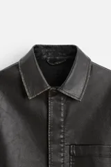 Sobrecamisa negra de manga corta confeccionada en tejido efecto piel, con cuello solapa, bolsillo frontal de parche y cierre frontal con botonadura oculta.