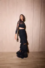 Falda larga de color negro confeccionada en microtul y encaje. Presenta un diseño con frunces en la zona de la cadera, volados escalonados que aportan movimiento y una abertura lateral pronunciada. Cuenta con forrería interna en la parte superior.