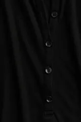 Remera polo negra entallada de punto transparente, de manga larga con cuello clásico y tapeta de botones.