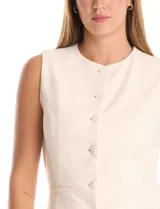 Chaleco sastrero color crema, con cuello redondo, cierre frontal con botones forrados y bolsillos simulados. El ruedo frontal tiene un acabado en pico.