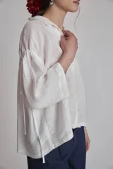 Camisa blanca de lino con cuello clásico, cierre frontal con botones y mangas 3/4 abullonadas.
