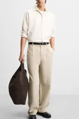 Pantalón color beige de corte ancho, con pliegues frontales, bolsillos laterales y traseros de doble vivo.