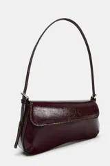 Bolso de hombro color crema con efecto acharolado, solapa con cierre imantado y asa ajustable.