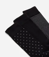 Set de tres pares de medias de caña alta, confeccionadas en algodón. Un par es liso color negro, otro par es negro con lunares blancos y el tercero es negro con rayas horizontales blancas.