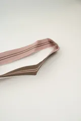 Bolso tipo bombonera tejido a crochet, con patrón geométrico en tonos rosa y marrón. Tiene cierre con cordón ajustable y correa de hombro.