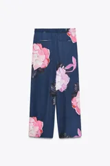 Pantalón de tiro alto con estampado de flores rosas y lilas sobre fondo azul marino. Tiene bolsillos delanteros y falsos bolsillos traseros. La cintura es elástica y ajustable con cordones.