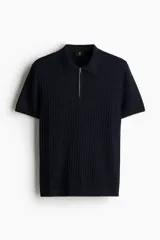 Remera polo de manga corta color azul marino en punto acanalado de mezcla de algodón con cuello y medio cierre. Remate acanalado de raya fina en mangas y bajo. Corte ajustado que realza el contorno del cuerpo creando una silueta entallada.