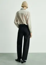 Pantalón de jean negro de corte slouchy, tiro alto, cinco bolsillos, cierre de cremallera y botón.