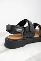 Sandalias negras con textura símil piel de cocodrilo, con ajuste de velcro y suela track.