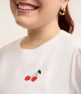 Blusa blanca de algodón con cuello redondo, manga corta abullonada y estampado de cerezas.