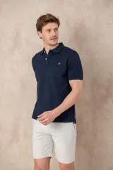 Chomba azul marino de piqué con cuello clásico, tapeta de dos botones y logo de pájaro bordado en color rosa en el pecho.