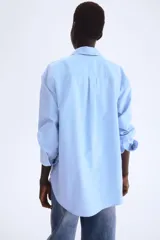 Camisa celeste de algodón Oxford, de corte relajado, con cuello clásico, botones frontales, canesú con trabilla en la espalda, hombros caídos, mangas largas con puños sencillos y bajo redondeado con espalda algo más larga.
