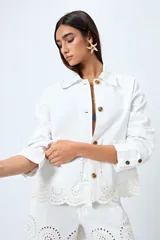 Sobrecamisa blanca de algodón con cuello camisero, botones marrones y detalles de encaje calado en el ruedo.