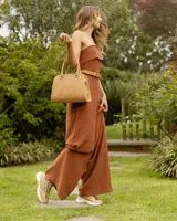 Zapatillas deportivas color beige con detalles dorados, cordones al tono y suela blanca.