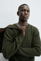 Sweater verde oscuro de punto, con cuello redondo y manga larga. Tejido en hilatura con mezcla de lana y acabados en rib.