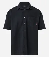Camisa negra de sarga, corte boxy, con cuello inglés, manga corta, abotonadura frontal y bolsillo en el pecho.