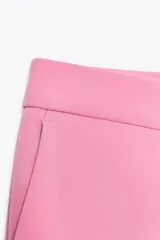 Pantalón color arena de tiro alto con bolsillos delanteros y corte acampanado. Cierre frontal con cremallera y gancho metálico.