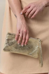 Cartera sobre de cuero dorada, ideal para llevar en la mano, con cierre y diseño minimalista.