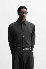 Camisa color crema de corte relaxed fit, confeccionada en tejido de mezcla de algodón suave al tacto. Tiene cuello solapa, manga larga con puños abotonados, un bolsillo de parche en el pecho y cierre frontal con botones.