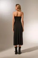 Vestido negro sin mangas, de corte ajustado al cuerpo y largo midi, con escote strapless.