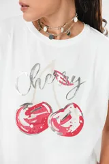 Remera blanca de algodón con estampa de cerezas y texto en color plateado.