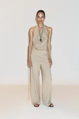 Top color beige confeccionado en algodón 100% con efecto teñido. Presenta cuello halter con lazada y escote drapeado. El bajo tiene un acabado asimétrico.