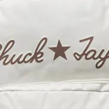 Mochila Converse color gris claro con logo "Chuck Taylor" bordado en marrón. Tiene un compartimento principal con cierre, un bolsillo frontal con cierre y un asa de mano en la parte superior.